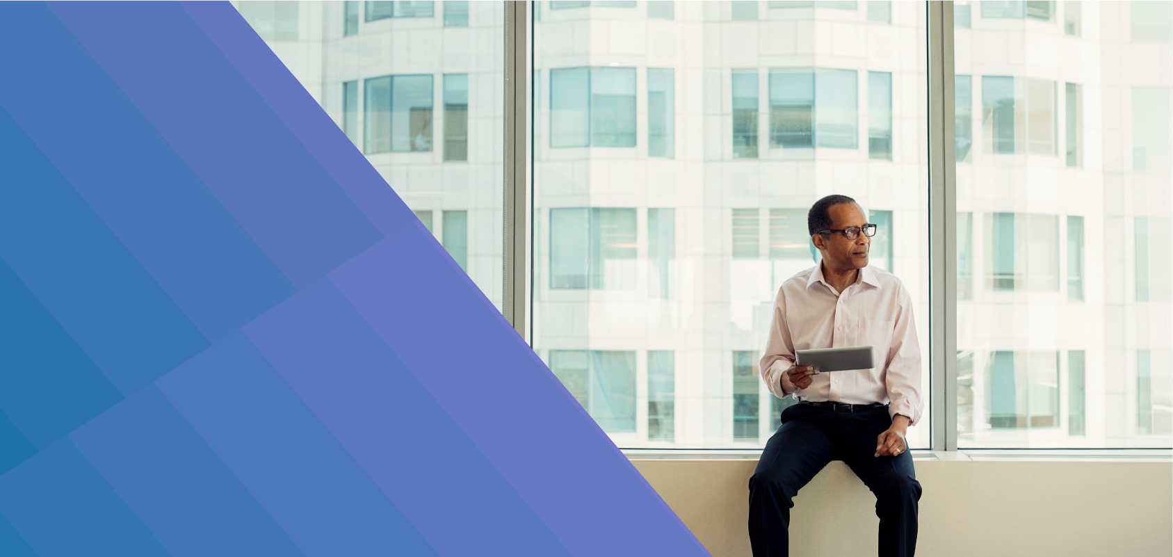 Businessman sitting on window sill with iPad