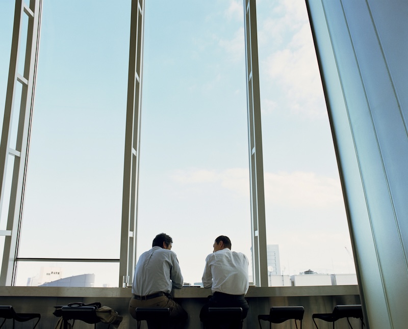 Two businessmen chatting in front of an airport window